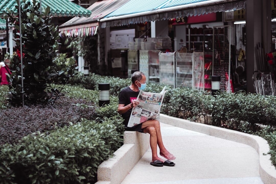 elderly man on bench reading newspaper